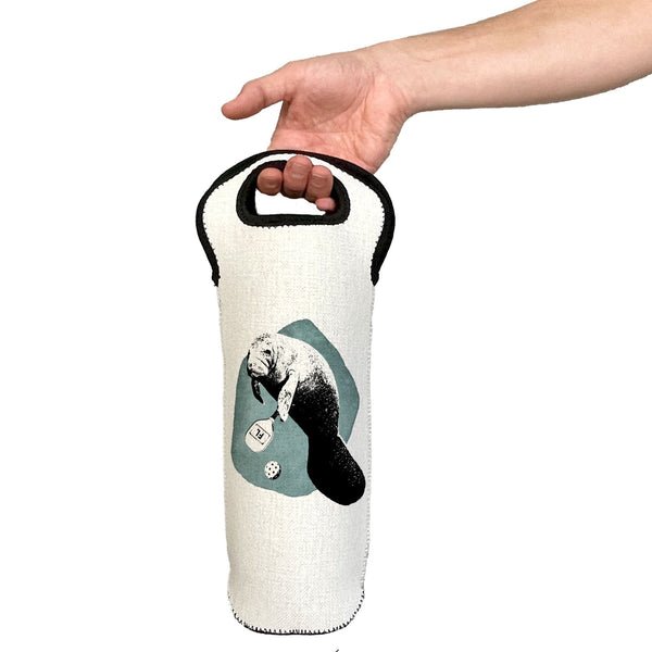 Hand holding a white wine bottle bag with a design of a manatee on a white background