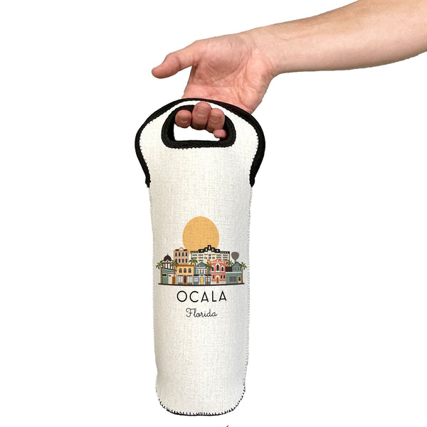 Hand holding a white wine bottle bag with 'Ocala, Florida' design on a white background