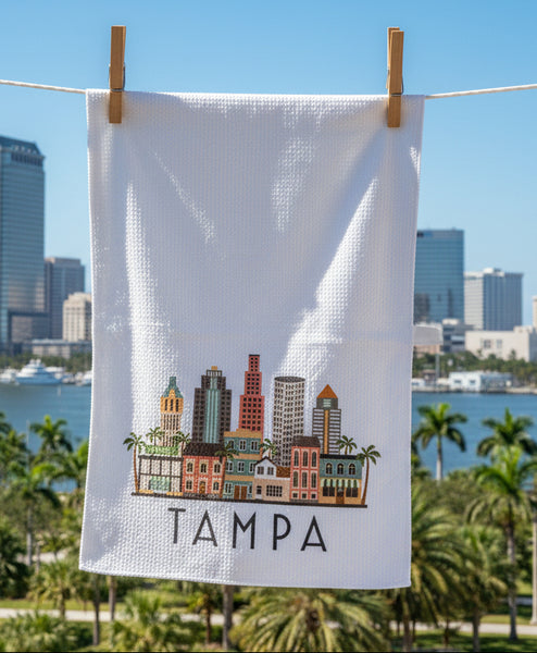 White towel with a colorful illustration of Tampa's skyline and the word 'Tampa' on a gray background