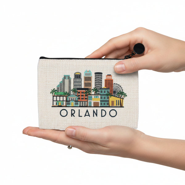 A small zip pouch with a cream-colored canvas background featuring a colorful illustrated skyline of Orlando, Florida, with the word 'ORLANDO' printed below. The pouch has a black zipper and a black pom-pom charm on the zipper pull.